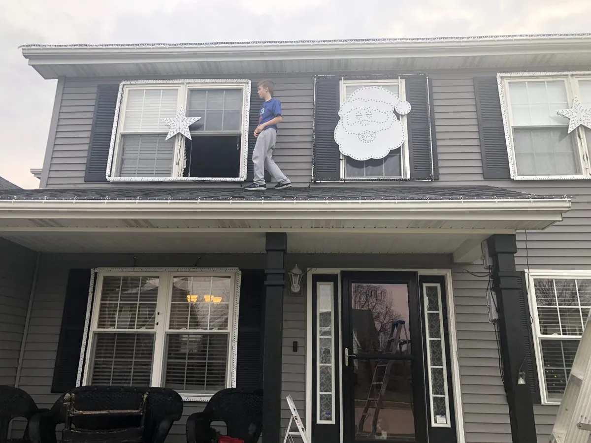Max hangs santa on the old house, 2019