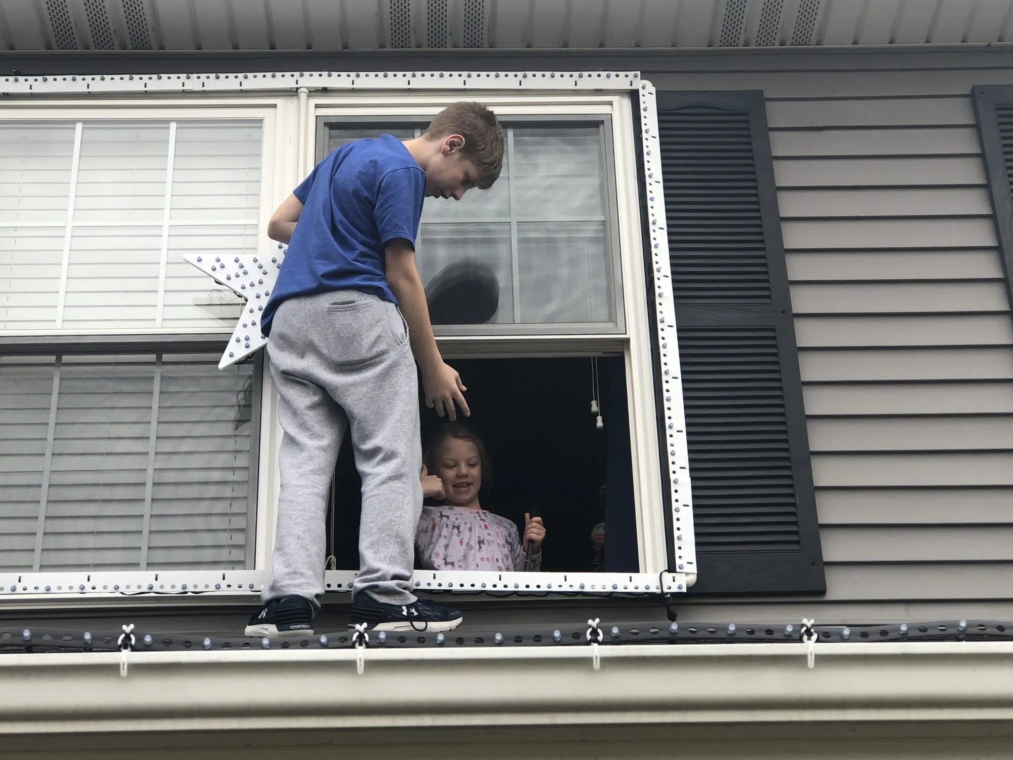 Max on the porch roof, with Violet helping from inside, 2019